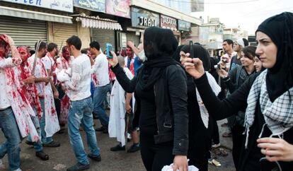 Un grupo de chicas fotografían a participantes en el día de Ashura.