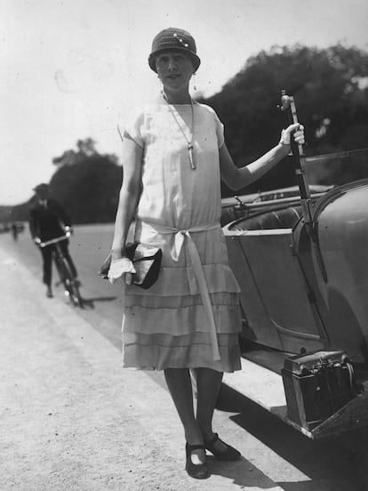 Una modelo lleva un vestido de verano con volantes y cartera de piel.