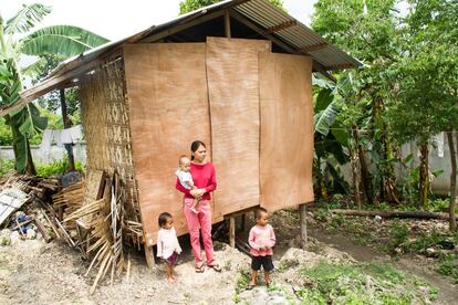 Cheryl posa junto a sus tres hijos en frente de su casa recién reparada en Borbón, Cebú.