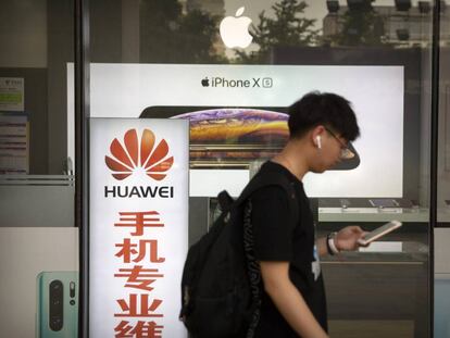 Un hombre camina junto a una tienda con anuncios de Huawei y Apple, en Pekín, el pasado viernes.