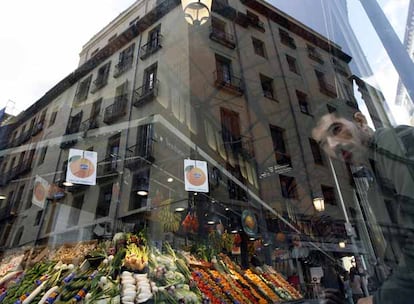 Puesto de frutas y verduras tras la fachada de cristal del renovado mercado de San Miguel.