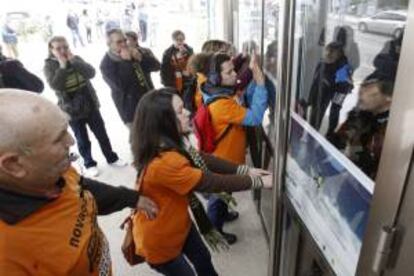 Afectados por las participaciones preferentes y subordinadas de Novagalicia banco golpean las puertas del Ayuntamiento de Nigrn (Pontevedra), durante una protesta. EFE/Archivo