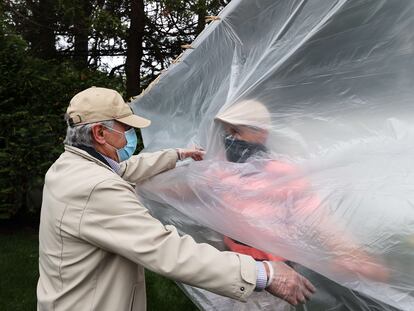 Un hombre abraza a su padre a través de un plástico en la celebración del día de los caídos en Wantagh, Nueva York, este domingo.