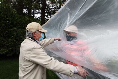 Un hombre abraza a su padre a través de un plástico en la celebración del día de los caídos en Wantagh, Nueva York, este domingo.