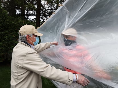 Un hombre abraza a su padre a través de un plástico en la celebración del día de los caídos en Wantagh, Nueva York, este domingo.