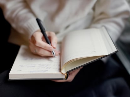 Una persona escribe en un cuaderno.