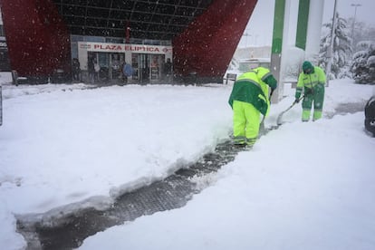 Dos operarios municipales limpian la nieve en los alrededores de la estación de Plaza Elíptica, en Madrid.