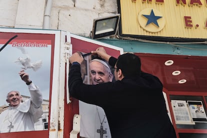 El dueño de una tienda coloca una cinta negra sobre una foto del difunto Papa tras la noticia de su fallecimiento a los 88 años, en Belén (Cisjordania), el lunes.