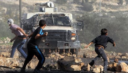 Palestinos lanzan piedras a un veh&iacute;culo militar israel&iacute; cerca de Nablus.