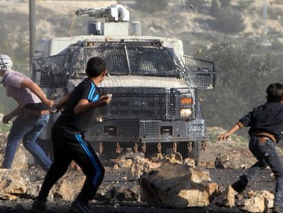 Palestinos lançam pedras em veículo militar israelense.