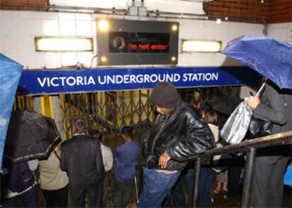 Varios viajeros esperan en el exterior de la estación de metro de Victoria, afectada por el apagón.