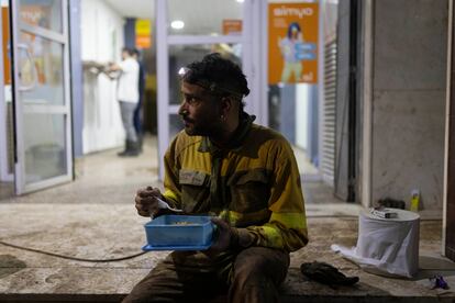 Un bombero de  Castilla y Len cena durante una pausa durante el trabajo de achique de agua en Algemes. 