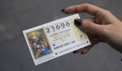 Una mujer muestra su numero de boleto de la lotería del Niño.