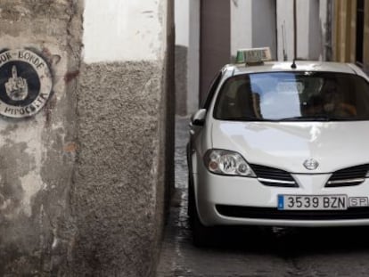 Un taxi avanza por la calle de San Juan de los Reyes, en el Albaic&iacute;n.