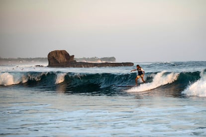 Una persona surfea en la playa de El Tunco, El Salvador.