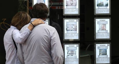 Una pareja observa anuncios de pisos en una inmobiliaria en Madrid