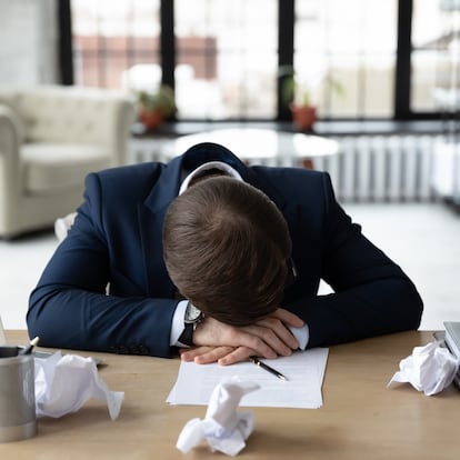 Exhausted Caucasian businessman feel tired after business report preparing fall asleep on office desk, overwhelmed male employee sleeping taking nap at table at workplace, overwork concept