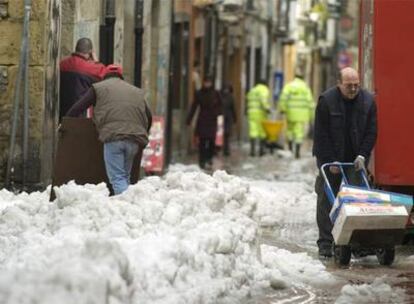 Un hombre transporta varias cajas dificultado por la nieve que todavía permanece en las calles de Vitoria, ciudad que recupera lentamente la normalidad tras dos días de intensas nevadas, que provocaron problemas de tráfico y alteraron la vida cotidiana