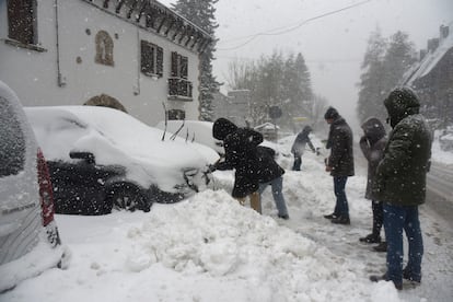 Turistas y vecinos de Canfranc (Huesca) quitan la nieve de sus coches, este domingo.