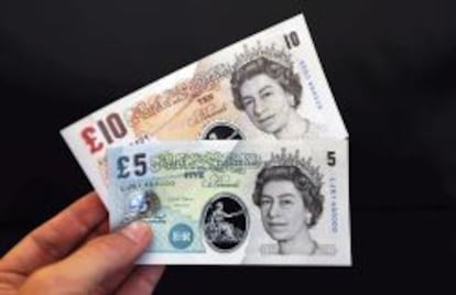 Una persona sostiene unos billetes de muestra de cinco y diez libras fabricados de un pol&iacute;mero pl&aacute;stico durante una rueda de prensa en el Banco de Inglaterra en Londres.