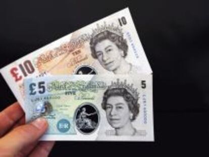 Una persona sostiene unos billetes de muestra de cinco y diez libras fabricados de un pol&iacute;mero pl&aacute;stico durante una rueda de prensa en el Banco de Inglaterra en Londres.