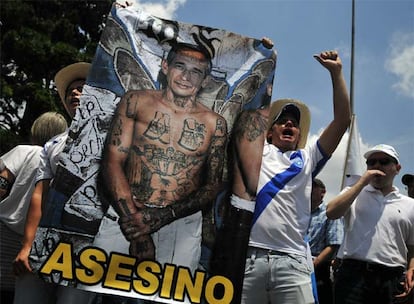 Dos manifestantes muestran un cartel acusando al presidente Colom del asesinato del abogado Rosenberg.