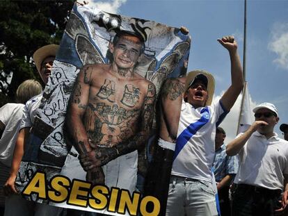 Dos manifestantes muestran un cartel acusando al presidente Colom del asesinato del abogado Rosenberg.