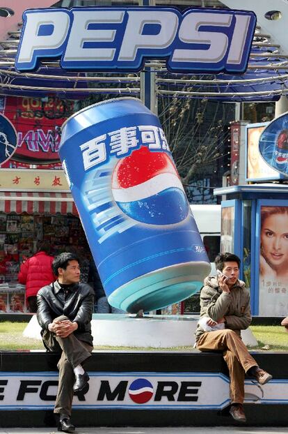 Dos habitantes de Shanghai, delante de un cartel publicitario.