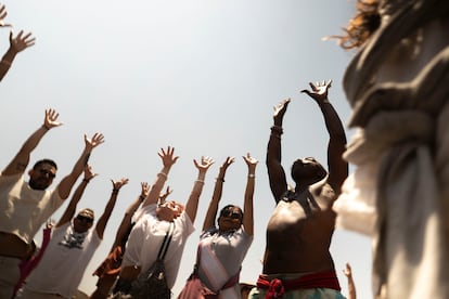 Visitantes de la zona arqueológica de Teotihuacán alzan sus manos al cielo durante una danza ritual.