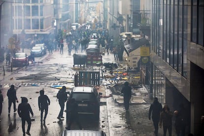 Varios manifestantes caminan entre los destrozos causados durante la protesta en contra de las medidas tomadas por las autoridades belgas para frentar la pandemia de coronavirus, este domingo en Bruselas.