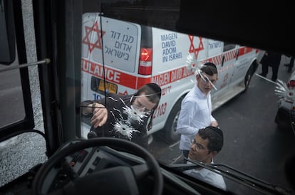 Varias personas observan el estado del autobús atacado en Jerusalén, este lunes.