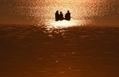 Tres personas viajan en un bote al atardecer sobre el lago Dal en Srinagar.