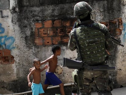 Crianças observam patrulhas das forças armadas durante uma operação contra traficantes no complexo de favelas de Lins, no Rio de Janeiro.