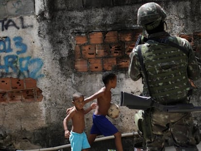 Crianças observam patrulhas das forças armadas durante uma operação contra traficantes no complexo de favelas de Lins, no Rio de Janeiro.