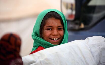 A displaced Syrian child, who fled the countryside surrounding the Islamic State (IS) group stronghold of Raqa, smiles while sitting at a temporary camp in the village of Ain Issa on April 28, 2017. / AFP PHOTO / DELIL SOULEIMAN