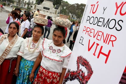 Tres mujeres junto a un cartel con la frase "Tú y yo podemos prevenir el VIH", durante el Día Mundial del sida, en Lima (Perú).