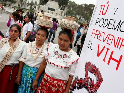 Tres mujeres junto a un cartel con la frase "Tú y yo podemos prevenir el VIH", durante el Día Mundial del sida, en Lima (Perú).