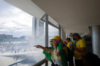 Varios manifestantes se cubren desde el interior de la nube de gas lanzada por la policía. 