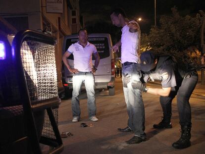 Un policía antidisturbios cachea a un hombre en la zona de bares de copas de Torrejón de Ardoz.