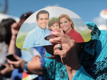 A woman shields herself from the sun using Rosselló campaign material.