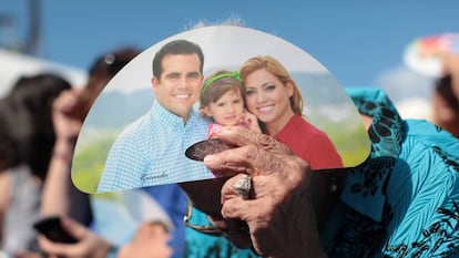 A woman shields herself from the sun using Rosselló campaign material.