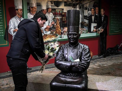 Un hombre deja un ramo de flores en la estatua de Bocuse en su restaurante en Lyon.