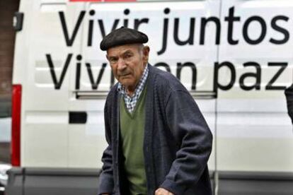 Un hombre camina por delante de un vehículo con un eslogan electoral, en Bilbao.