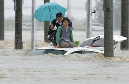 Los pasajeros de un coche que se ha hundido en las aguas tras el desbordamiento de un río, esperan en el techo del vehículo que los servicios de rescate los saquen de esta zona de la ciudad de Joso, al noreste de Tokio (Japón).