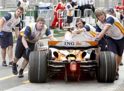 Mecánicos de Renault empujan el coche de Fernando Alonso tras una de las sesiones de entrenamientos de ayer.