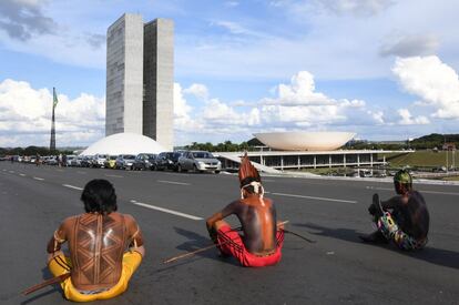 Tres indígenas bloquean el camino mientras se sientan frente al Congreso Nacional durante la marcha anual por sus derechos.