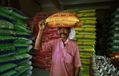 Retrato de un trabajador indio que transporta un saco de arroz en la cabeza en un almacén en Gauhati, India.