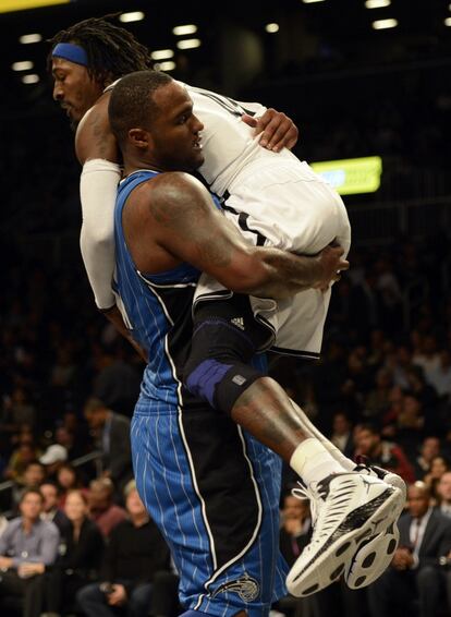 Glen Davis, de Orlando, apa a Gerald Wallace, de los Nets.