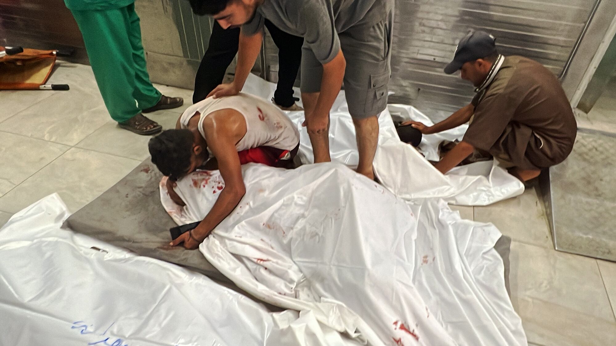 GAZA CITY, GAZA - JULY 26: A Palestinian man mourns next to lifeless body of a Palestinian wrapped in shrouds, at the morgue of Nasser Hospital after Israeli attacks hit the eastern areas of Khan Yunis, on July 26, 2024 in Gaza City, Gaza. The bodies of those who lost their lives were taken from the morgue to be buried by their relatives. It was reported that there were many dead and wounded, including children and women, as a result of the attack. (Photo by Abed Rahim Khatib/Anadolu via Getty Images)