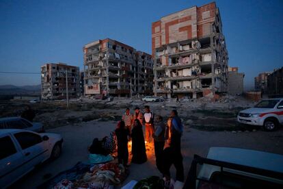 Residentes encienden un fuego junto a unos edificios destruidos tras el terremoto en la ciudad de Sarpol-e Zahab (Irán).